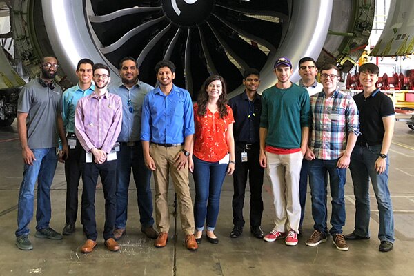 Group of 11 people in Hanger standing in front of Engine prop