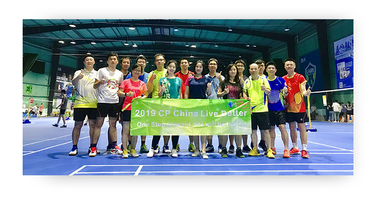 Employees in China standing in a badminton court holding the CP China Live Better programme banner