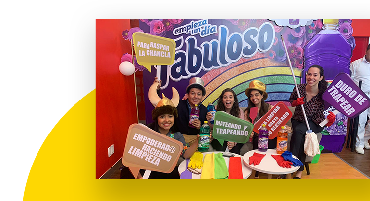 Employees holding signs with Spanish phrases in front a rainbow colored Fabuloso banner.
