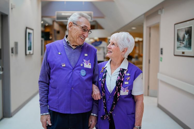 Portrait of a volunteer couple wearing volunteer vests sitting in the hospital cafeteria.