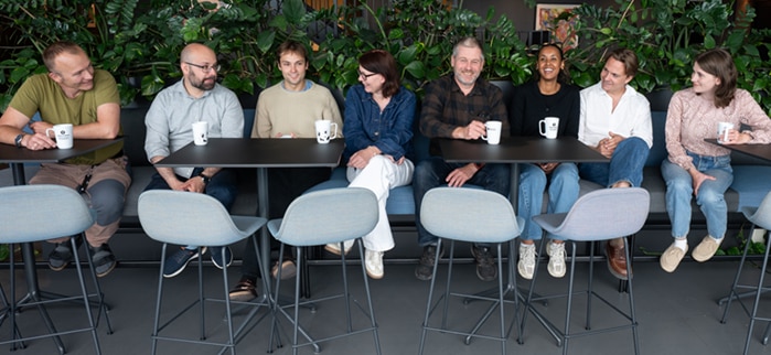 Åtte kollegaer i samtale i en sofa med grønne planter rundt seg. Foto: Statsforvalteren/Torbjørn Tandberg.