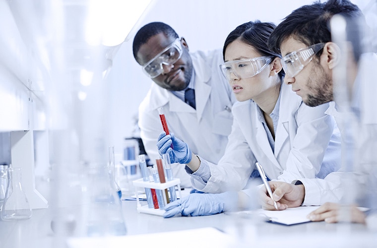 Two men and one woman in the lab with safety glasses
