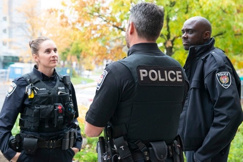 Une femme et deux hommes, agents de police du Service de police d'Ottawa, discutent à l'extérieur.