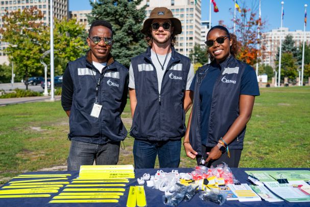 Four City of Ottawa employees standing in front of a building wearing blue shirts with the logo ‘How may I help you?’ support AccessAbility Day