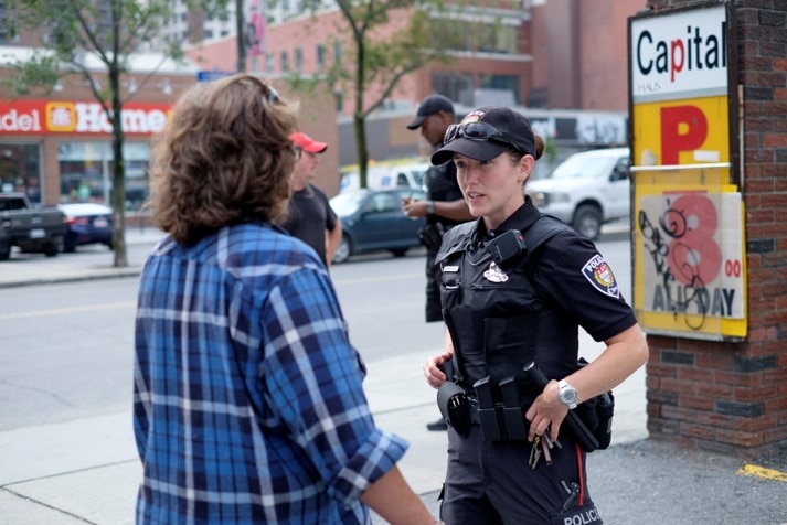 Female Ottawa Police Service officer standing outside speaking to a member of the public
