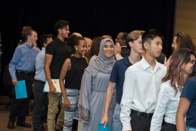 Groupe de jeunes faisant la queue pour recevoir leur certificat de fin d'études dans un auditorium.