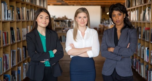 Three female law students standing in a library