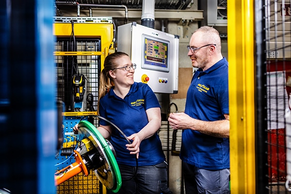 Two Goodyear production associates talking next to machinery