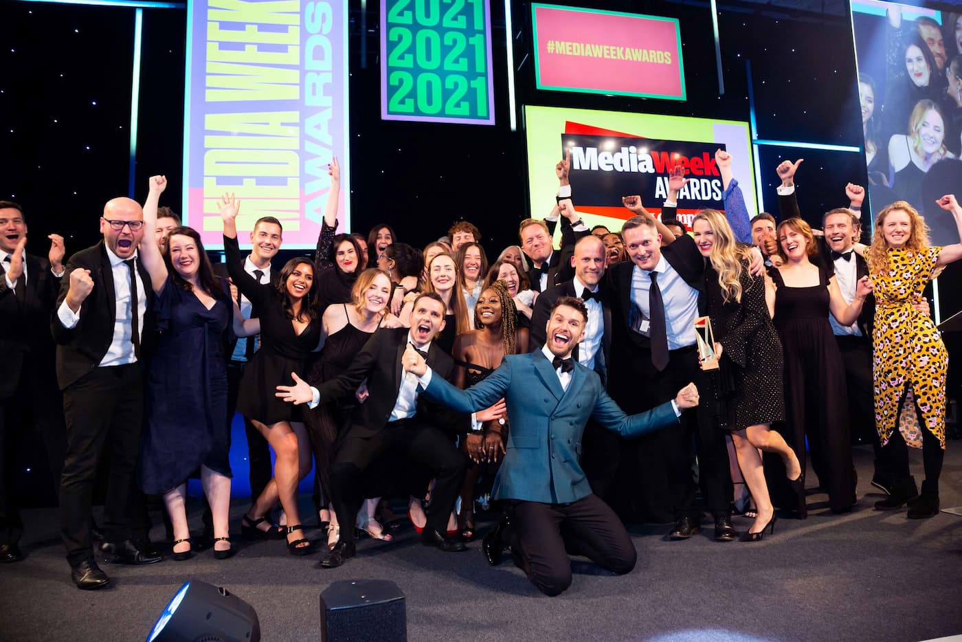 A group shot of MG OMD agency staff on the stage celebrating winning Media Week Agency of the Year