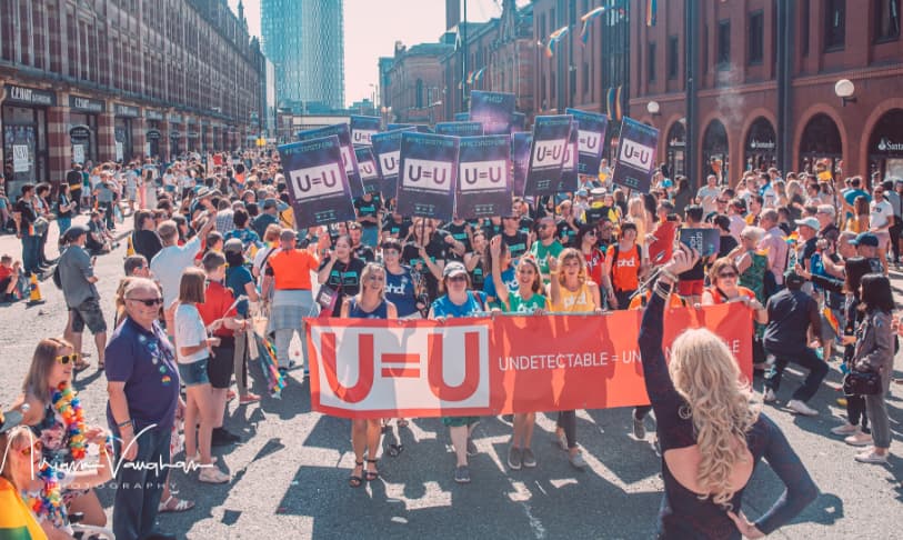 A picture of PHD staff marching at Manchester Pride 2019 holding banners with ‘Undetectable = untransmittable’