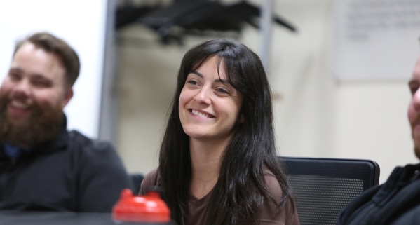 Employee with dark hair smiles with colleagues at a WCB Nova Scotia team meeting.