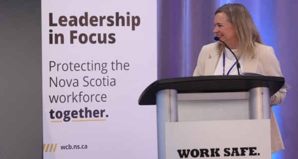 Shelly Dauphinee, WCB Nova Scotia Chief Engagement Officer, speaks at the Leadership in Focus meeting, with banner reading "Leadership in Focus – Protecting the Nova Scotia workforce together."