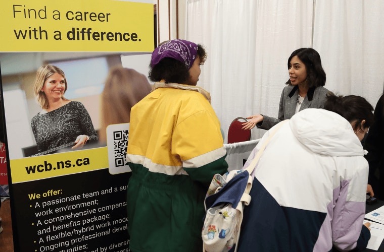 WCB Nova Scotia employee recruiting at a career fair booth with “Find a career with a difference” banner.