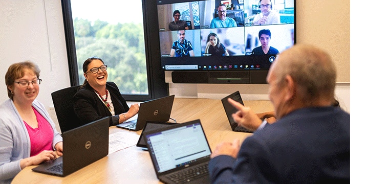Transport corporate office employees in a meeting room holding a meeting with colleagues online