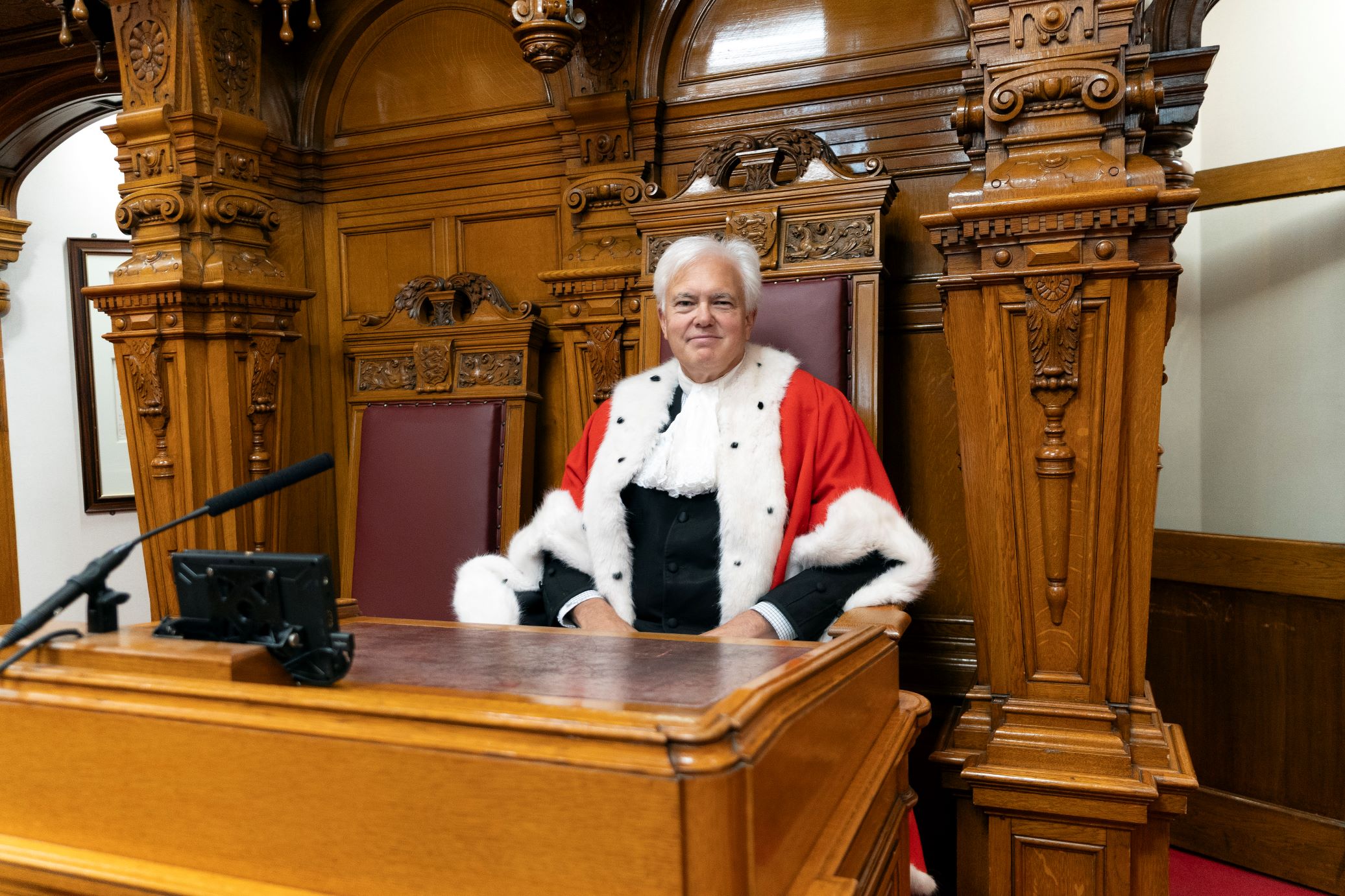 Bailiff Robert MacRae. He is wearing the traditional ceremonial robes, which are bright red with a cream fur trim.