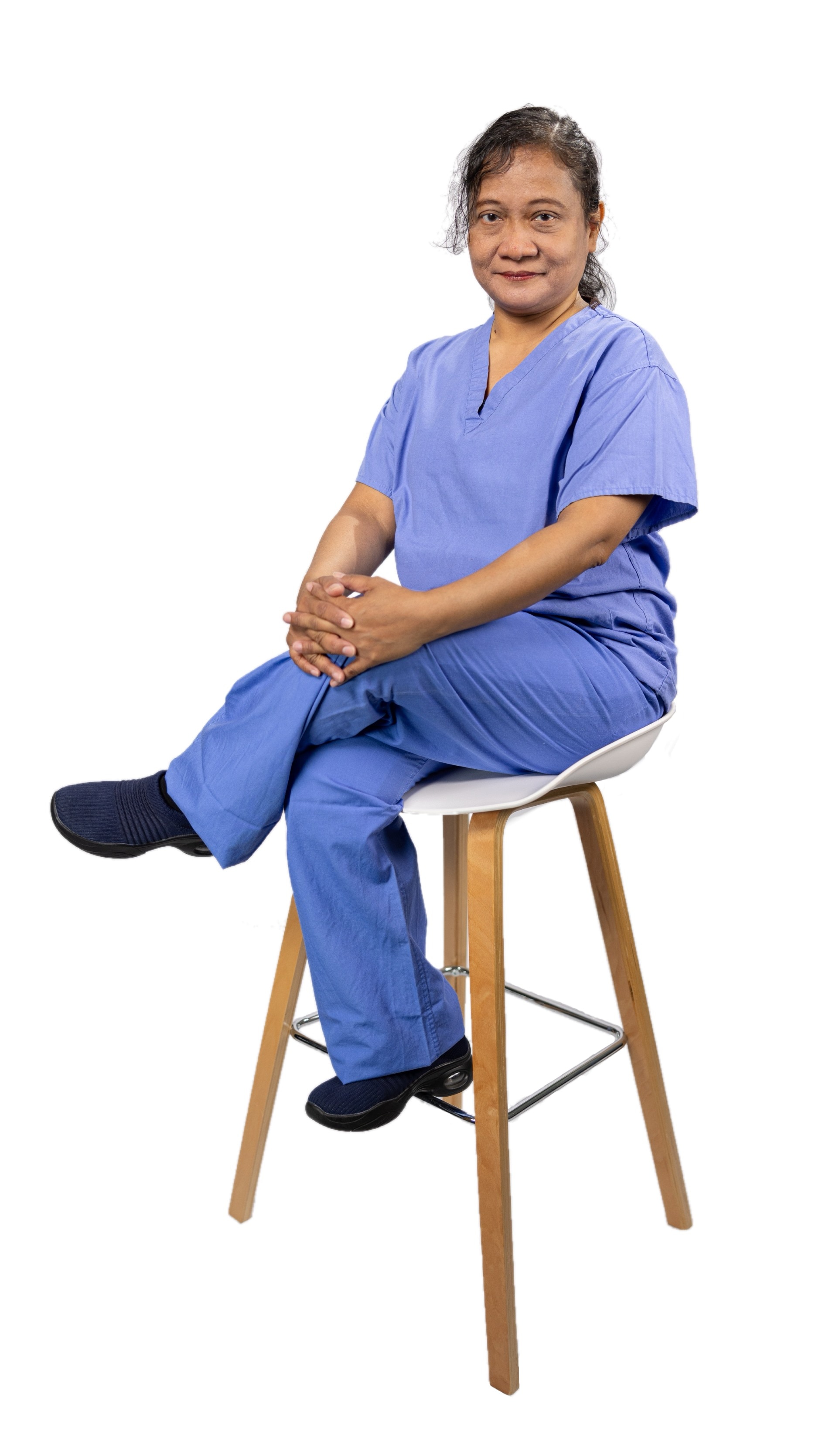 A woman in blue scrubs sits on a tall chair, representing apprenticeships