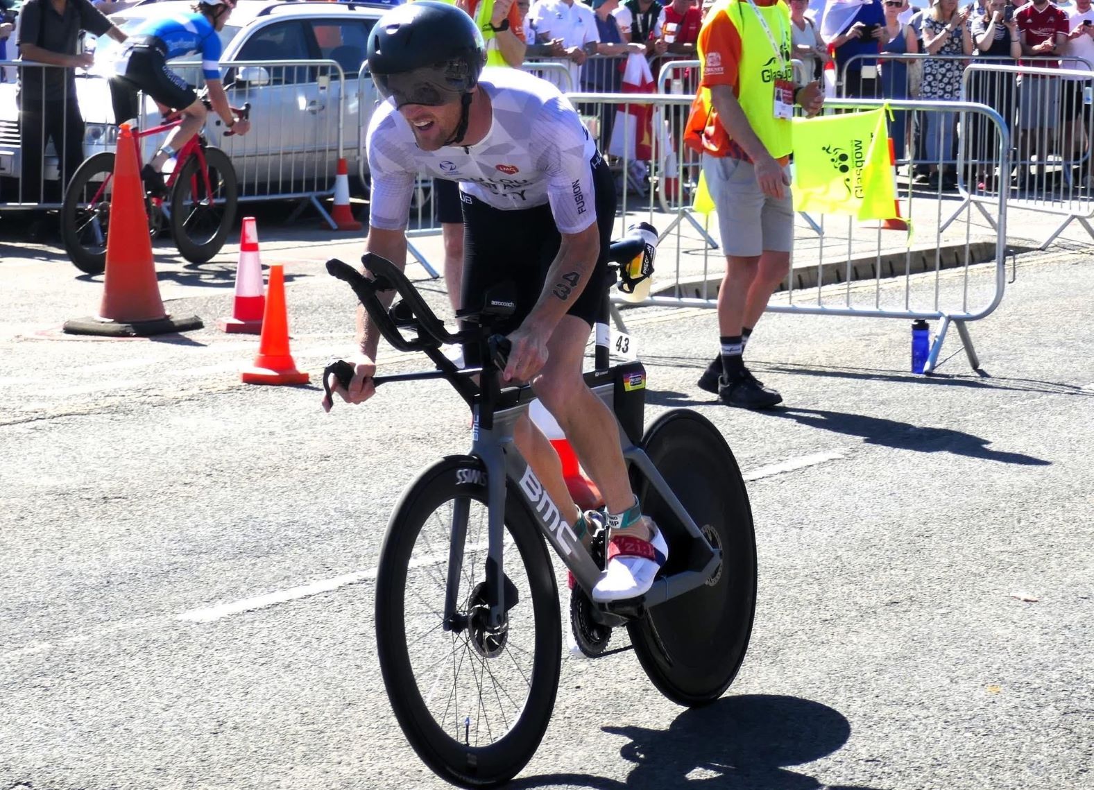 A man riding a sports bike with a large crowd in the background.