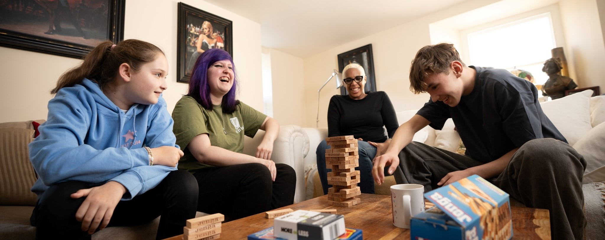 Four people are playing Jenga together. They are all smiling.