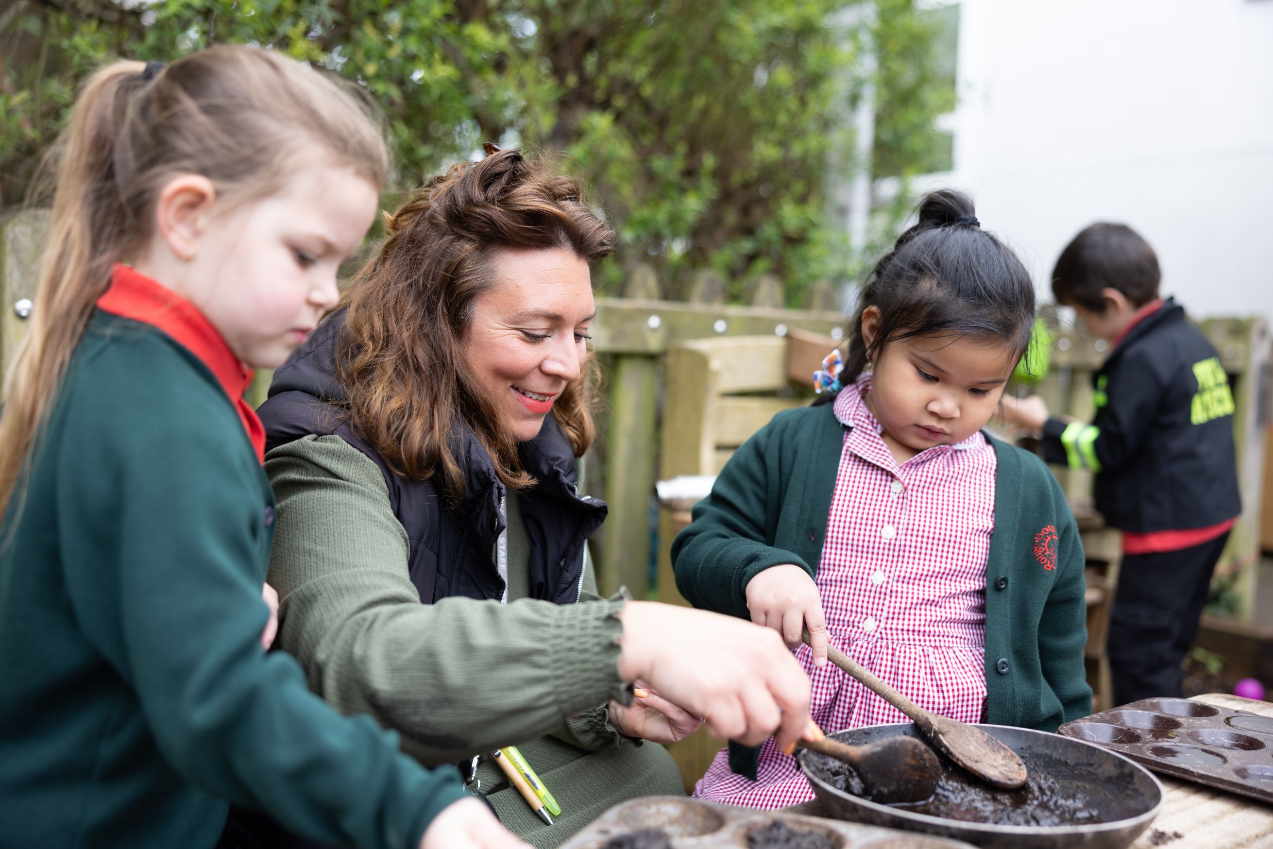 A lady with dark brown hair is seen cooking with two young children on either side of her