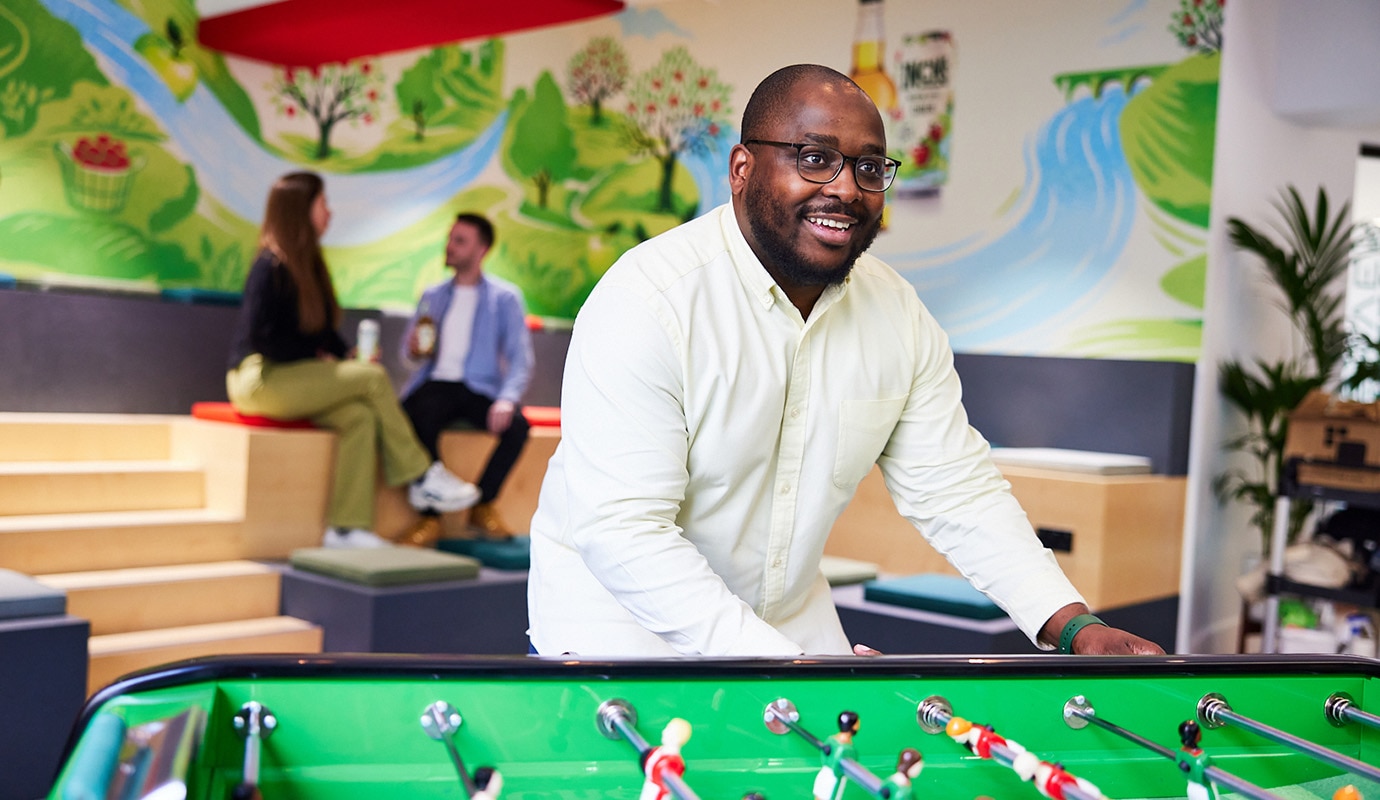 Male colleague in HEINEKEN's London office, playing table football and smiling.