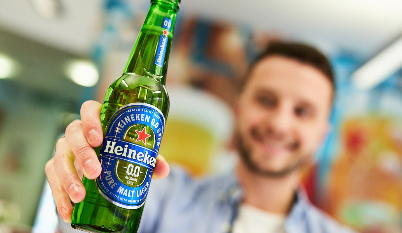 Male colleague in HEINEKEN's London office holding a bottle of Heineken 0.0 beer.