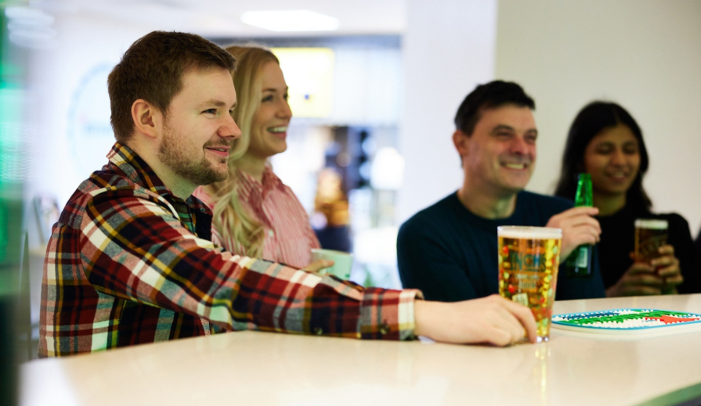 Colleagues stood and sat around the bar in HEINEKEN's Edinburgh office, smiling and chatting.