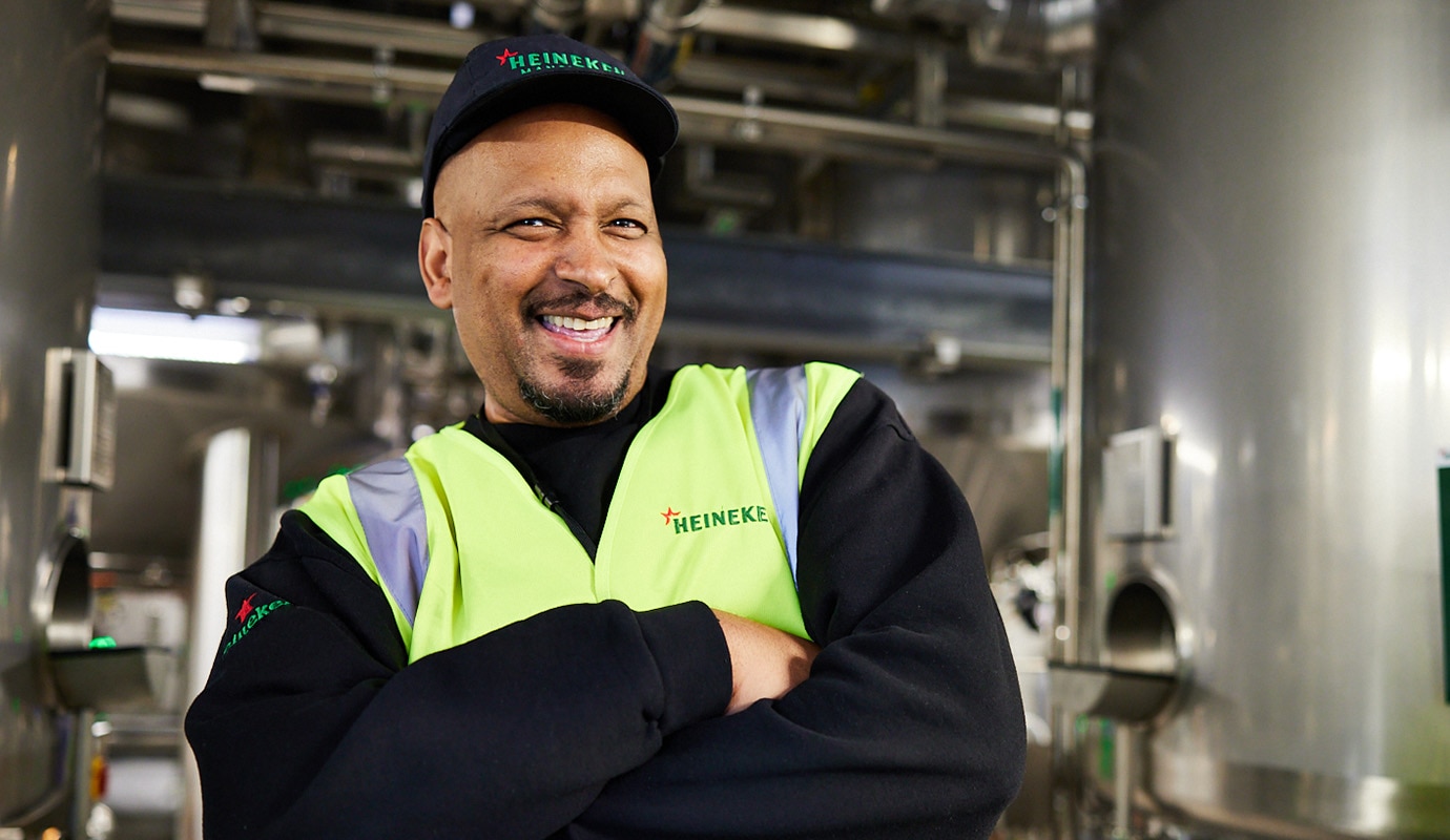 Male colleague at Manchester brewery, wearing a HEINEKEN high visibility vest and smiling.