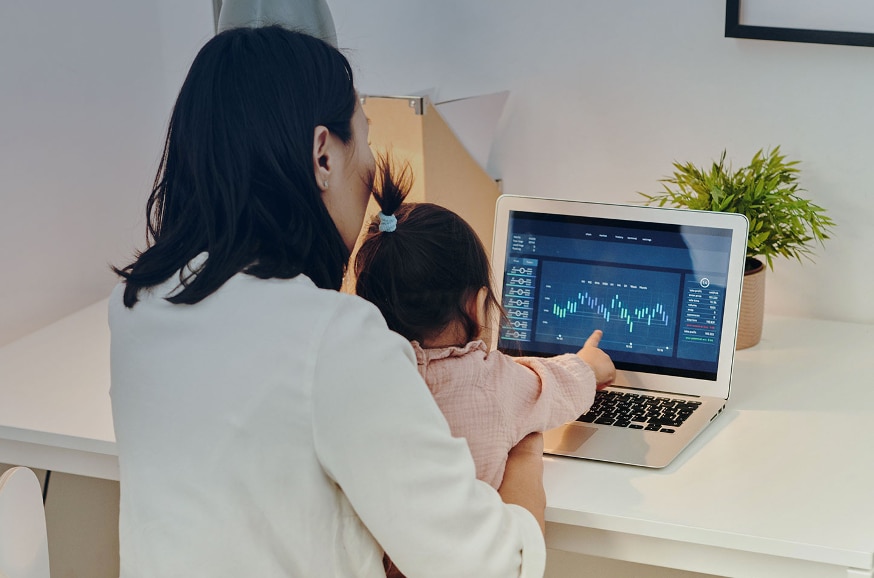 Woman holding a baby in her arms in front of her PC