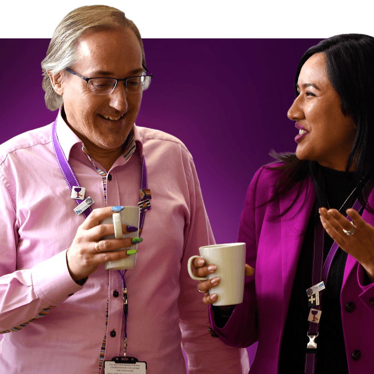 Two colleagues talking and laughing over a hot drink.