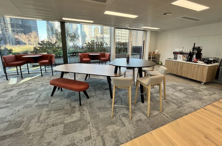 An open plan café area with tables and chairs and a place to make coffee, with views of the cityscape out of the window.