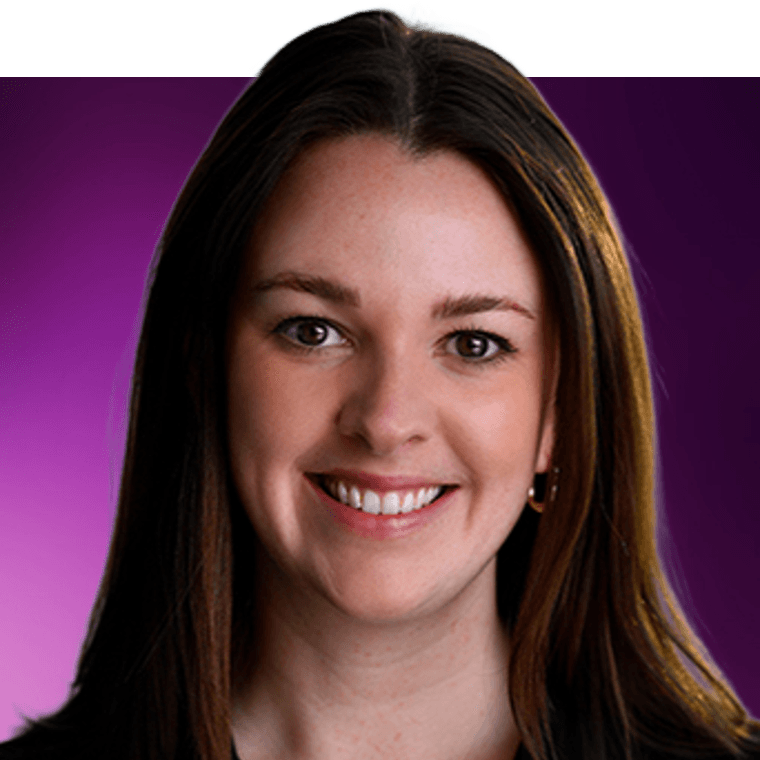 A colleague with brown hair wearing gold earrings and a black top smiling.