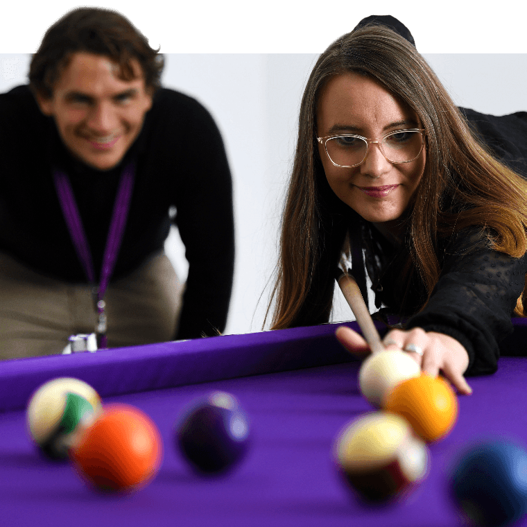 Colleagues playing a game of pool.