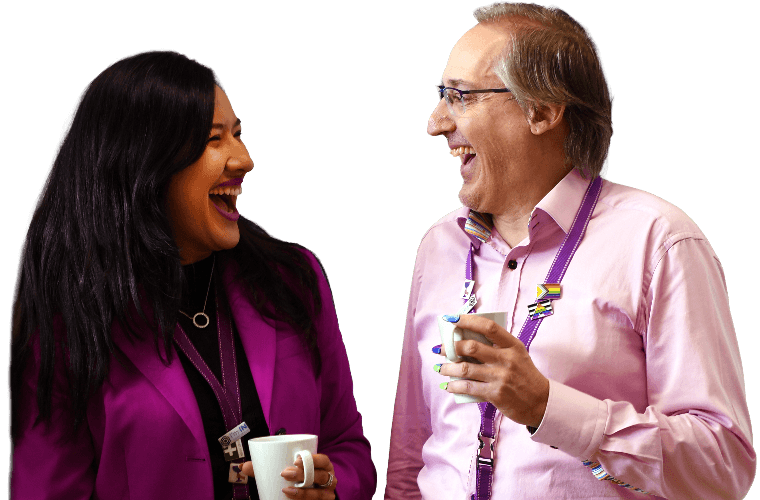 Two colleagues talking and laughing over a hot drink.