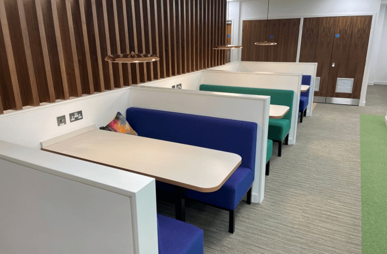 A collections of seating booths with a wooden panelled wall behind.