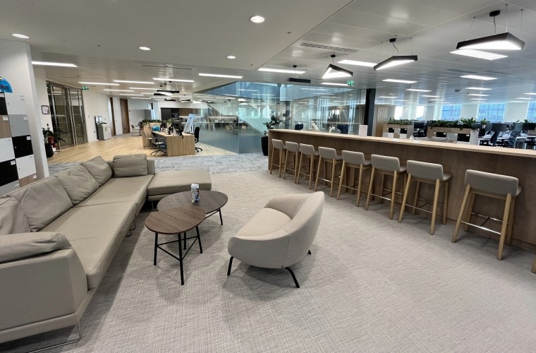 A long grey sofa and other seating in an open plan space.