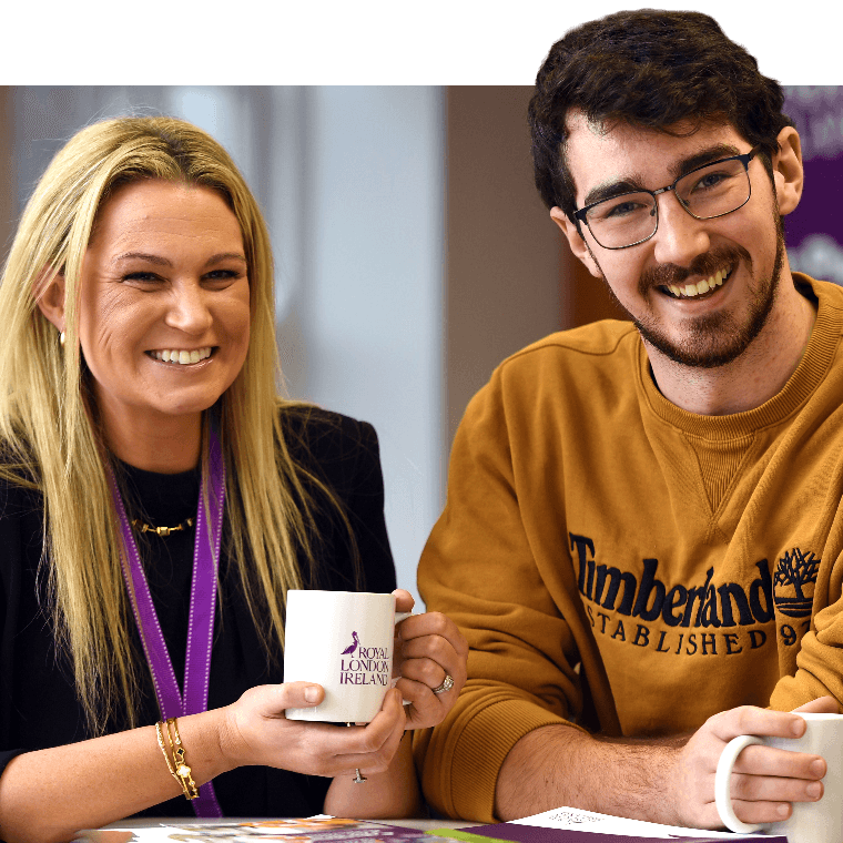 Two colleagues with hot drinks talking and smiling.