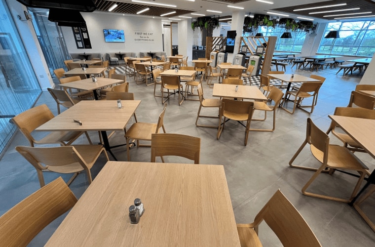 A restaurant with seating and columns with foliage hanging from the ceiling.