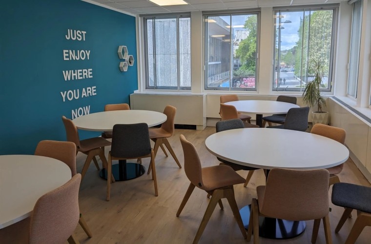 A kitchen with seating in front of a teal coloured wall.