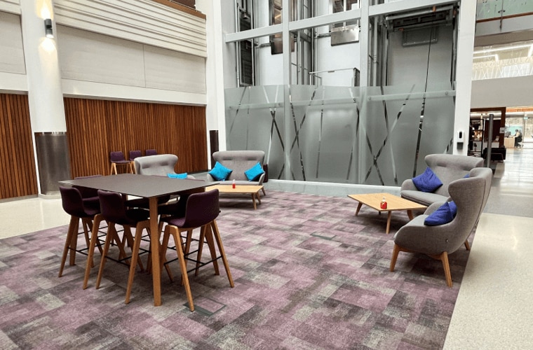 Seating in an open atrium on a purple carpet.