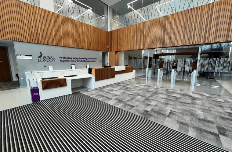 An open reception area with a white desk with wood panelling and the Royal London logo and Purpose on the wall.