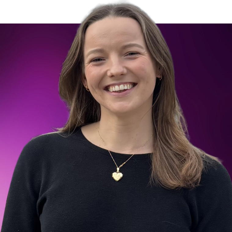 A colleague with long brown coloured hair wearing a black top and a gold heart pendant necklace against a purple background, they are smiling.