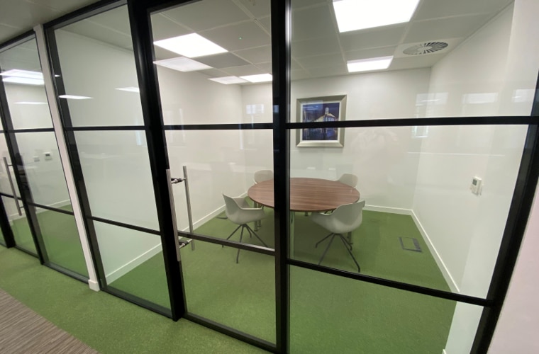 A meeting room behind a glass door with green carpet.