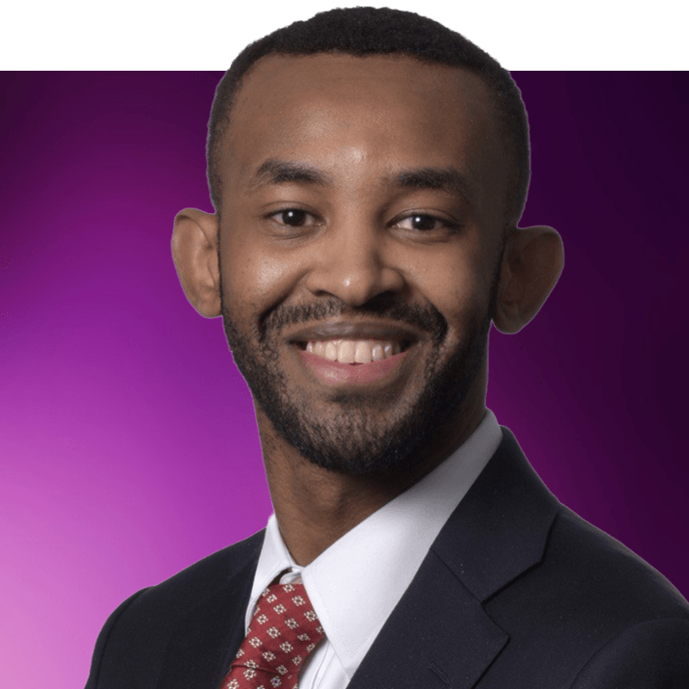 A colleague with black hair wearing a dark suit jacket over a white shirt and red tie, smiling.