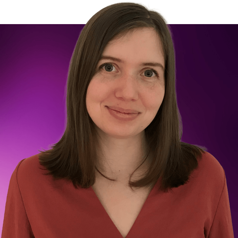A colleague with long brown hair, smiling, wearing a dark red orange top.