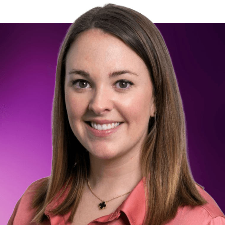 A colleague with long brown hair wearing a pink coloured short and a necklace smiling.