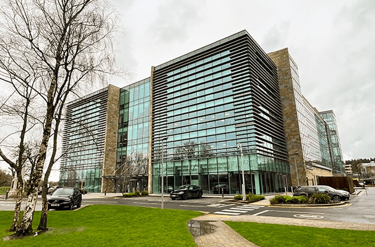 A building which appears to be made of glass with trees and bushes outside.