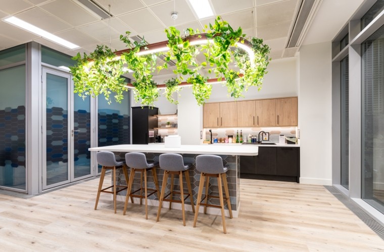 A seating area in a kitchen with a large plant covered light hanging from the ceiling.