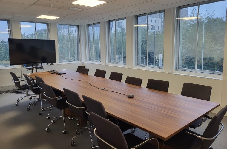 A meeting room with a large table in the centre and windows on all walls.