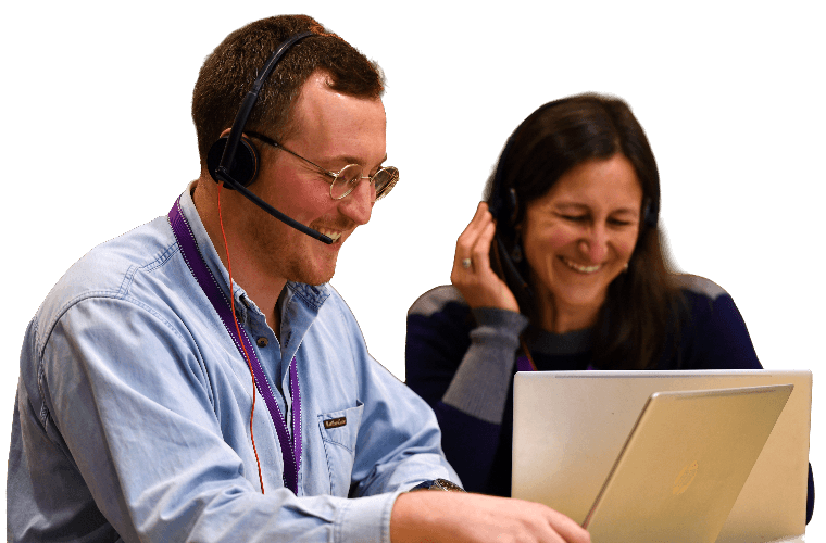 Two colleague sat at a laptop on a Teams call, smiling.