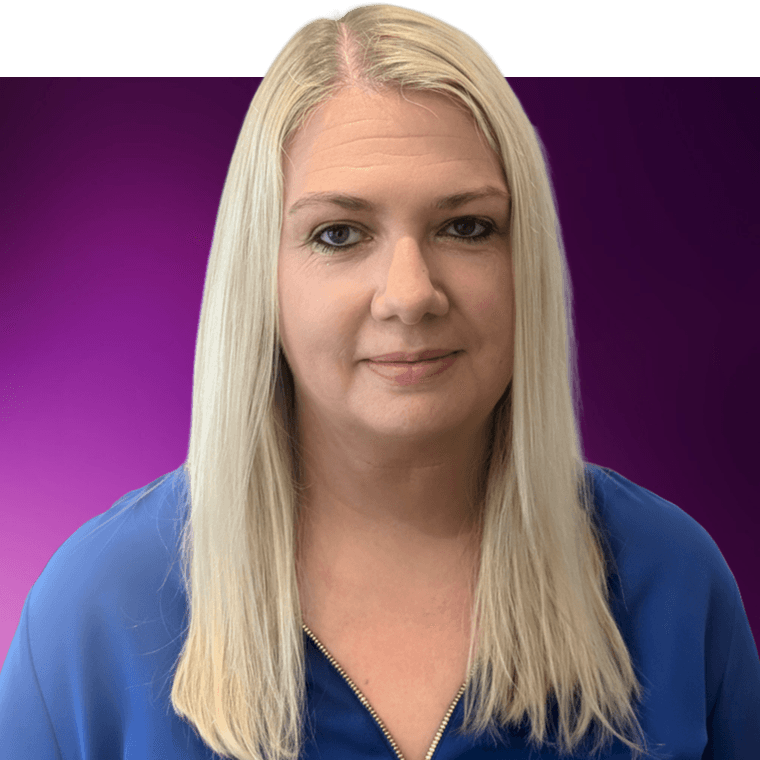 A colleague with light coloured hair wearing a blue cardigan over a black top.